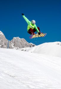 man in green jacket riding snowboard on snow covered mountain during daytime